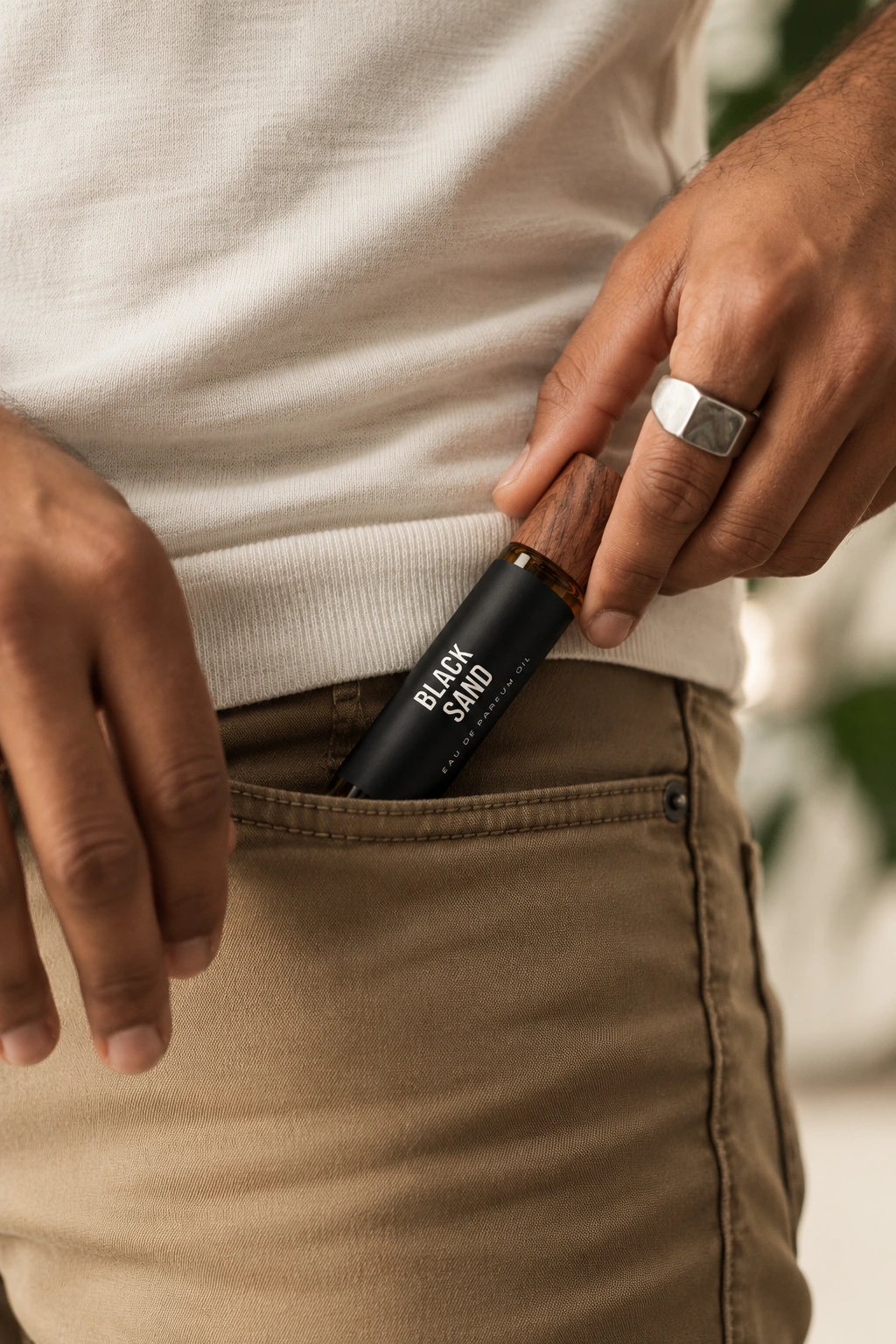 A gentleman placing Black Sand roll-on oil into his pants pocket